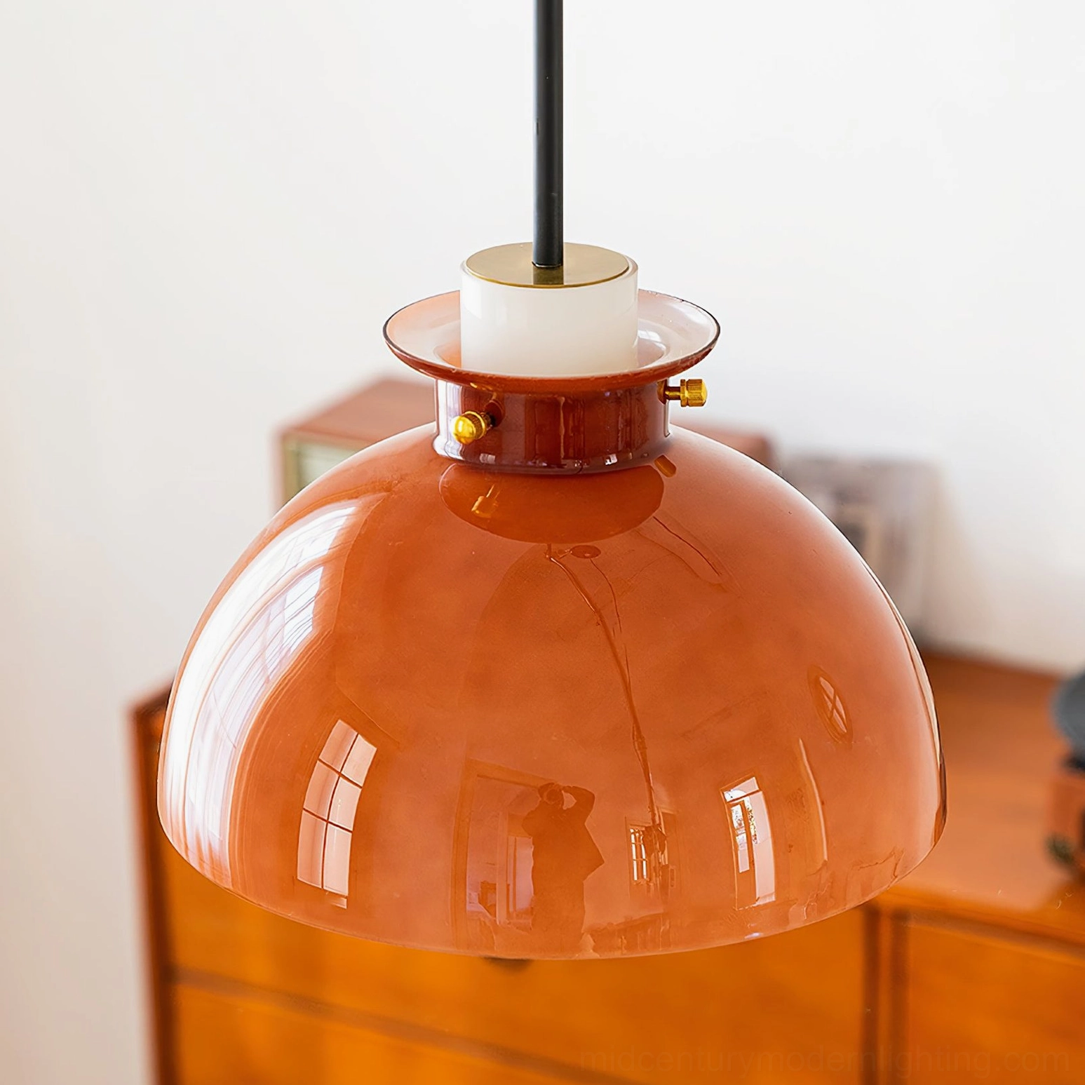 Cabras mid-century pendant light with glossy caramel shade in vintage home interior, front oblique view showing brass details