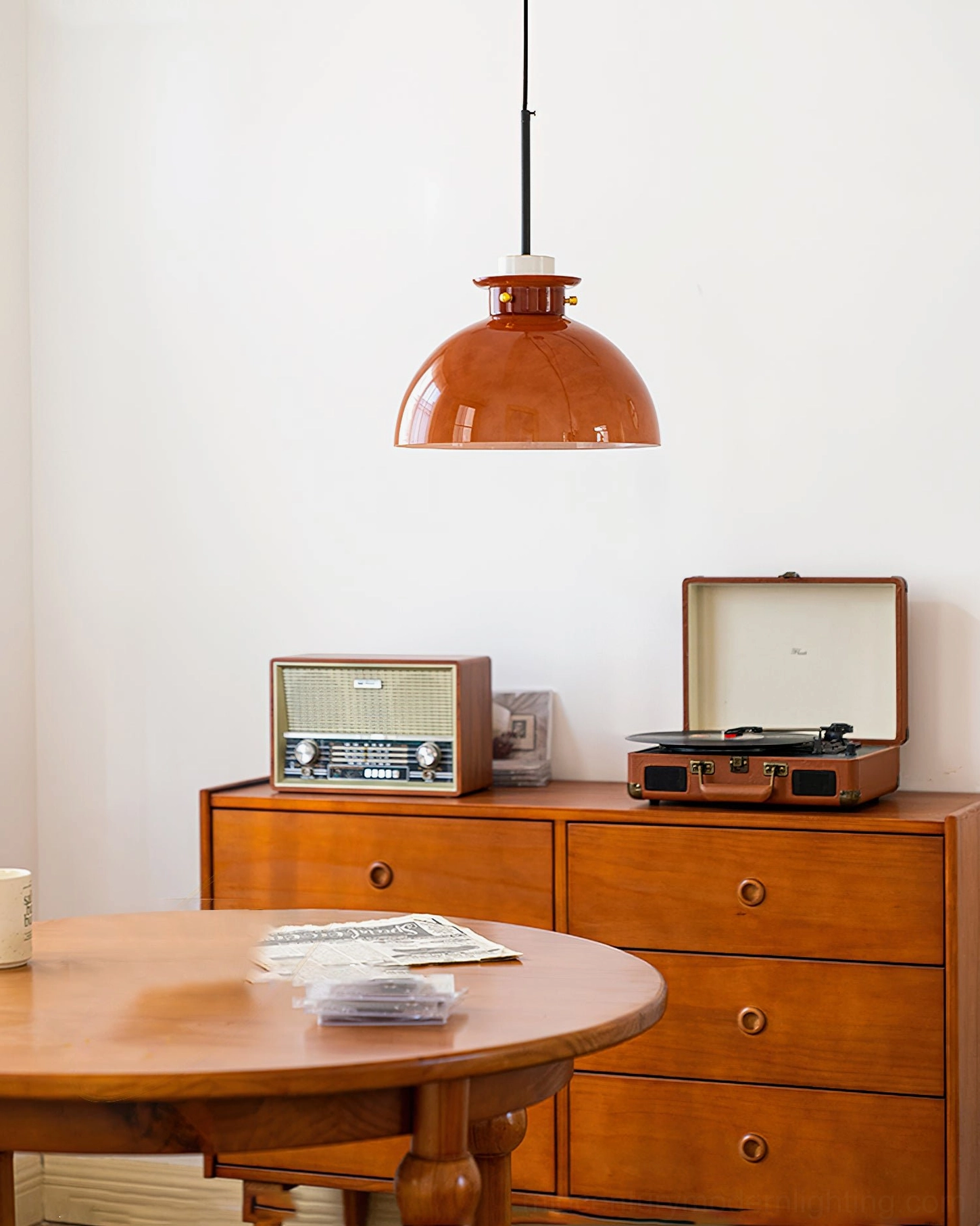 Cabras mid-century pendant light with compact dome shade and black suspension rod in vintage home living area, wide side angle