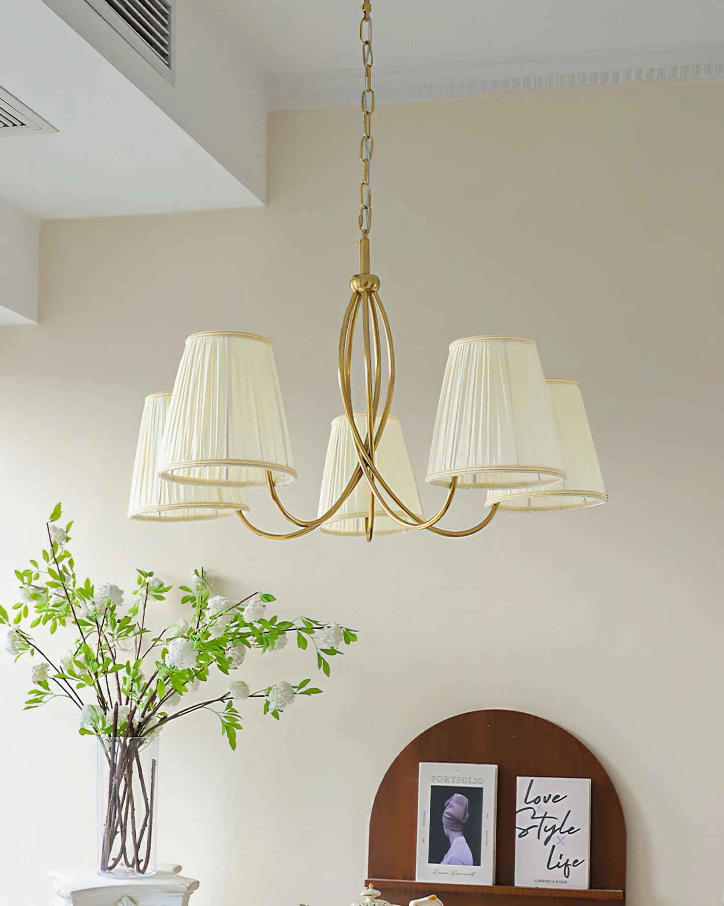 Calistoga 5-light chandelier three-quarter view with green leaf decor and botanical wall art