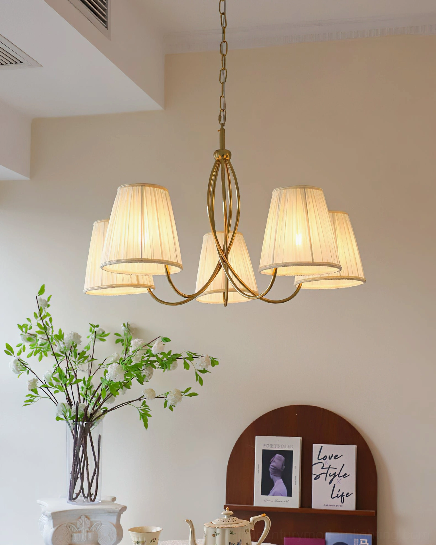 Calistoga brass chandelier matched with green floral arrangement in residential living space