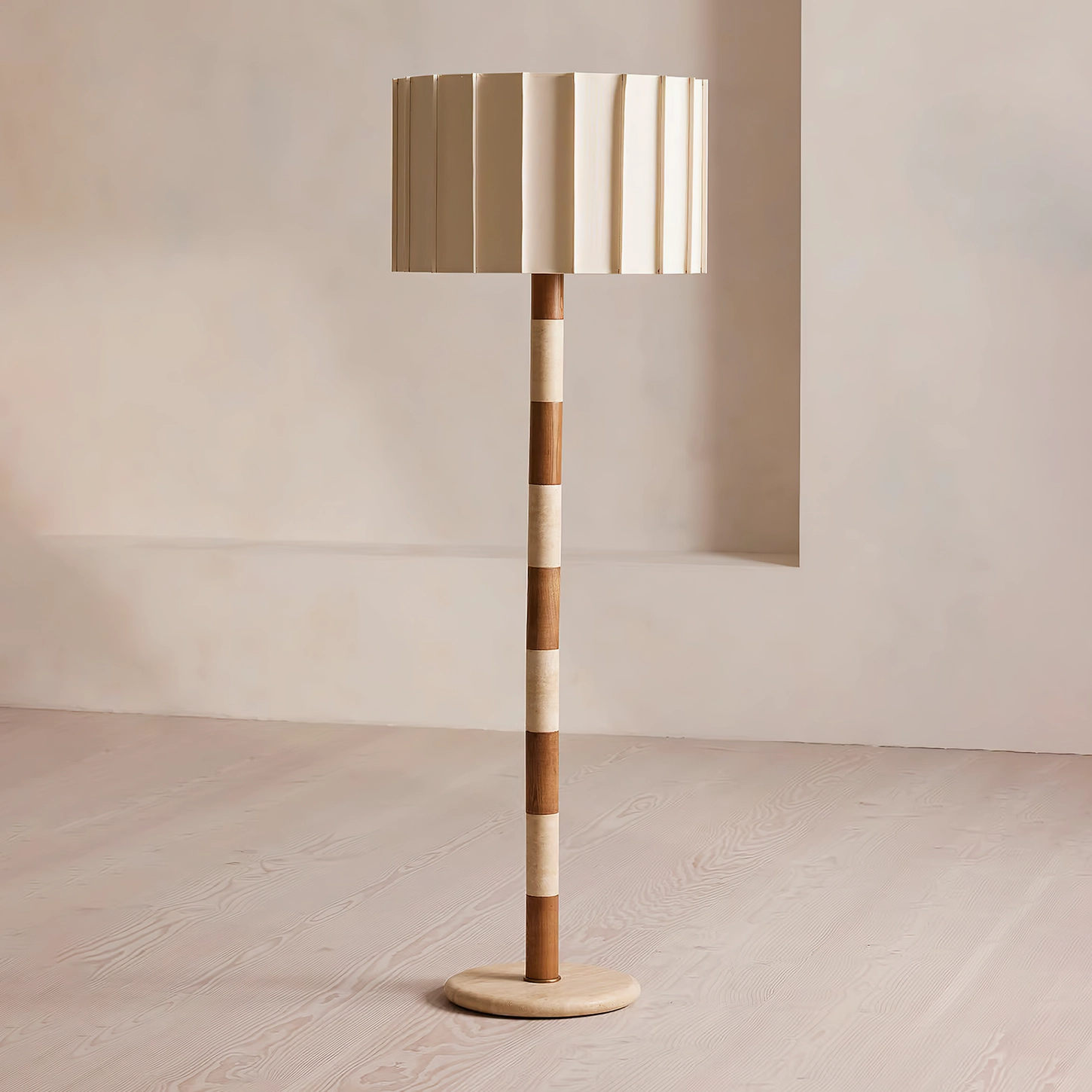 Calypso floor lamp with two-tone striped column in minimalist living room with light wood flooring, brass base and travertine details
