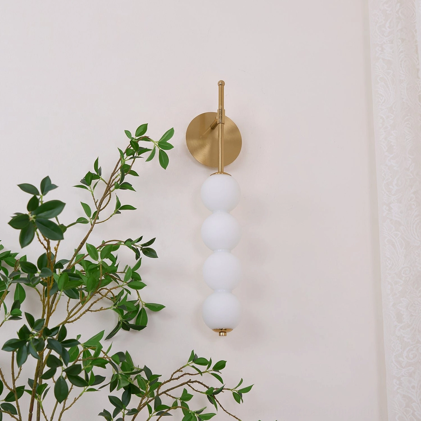 Close-up of Candied Haws wall sconce with five frosted white glass spheres and brass gold hardware