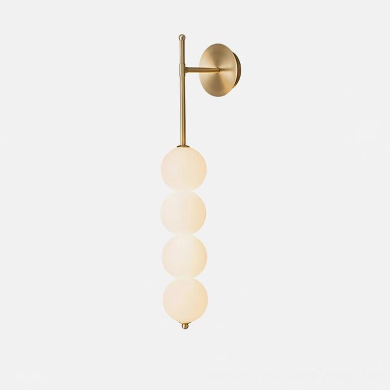 Gold brass Candied Haws sconce with frosted glass globes illuminated in warm light