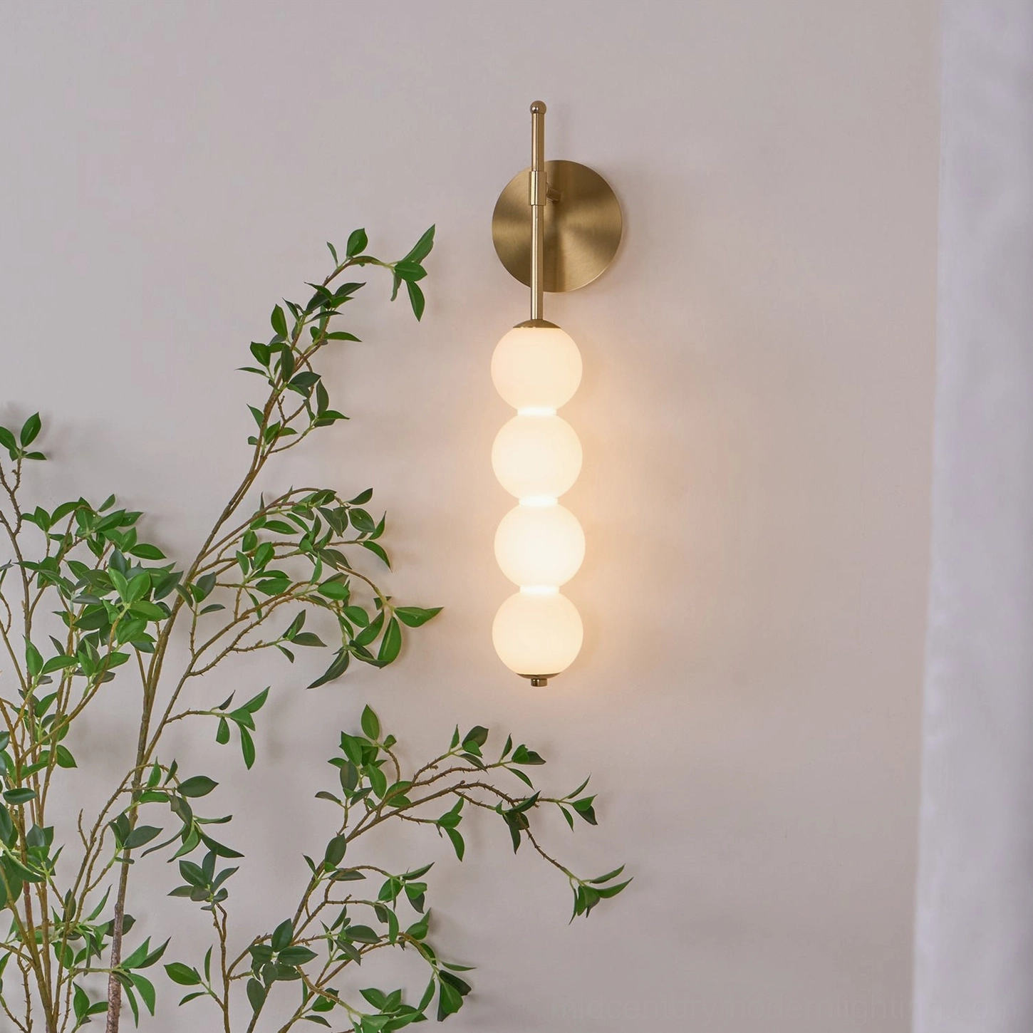 Lit Candied Haws brass sconce with warm ambient glow, illuminated frosted glass globes creating soft shadow play