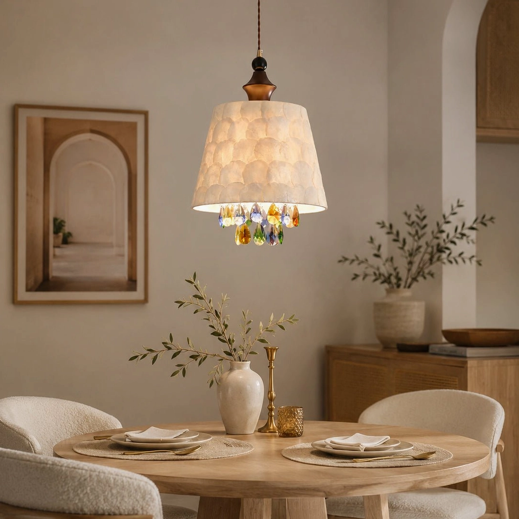 Capiz shell pendant light hanging above compact dining nook with light wood round table and potted decorative plants