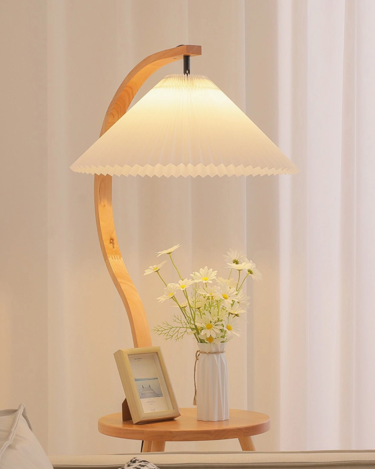 Caprani floor lamp with illuminated shade in cozy living room, side table decorated with flowers and photo frame