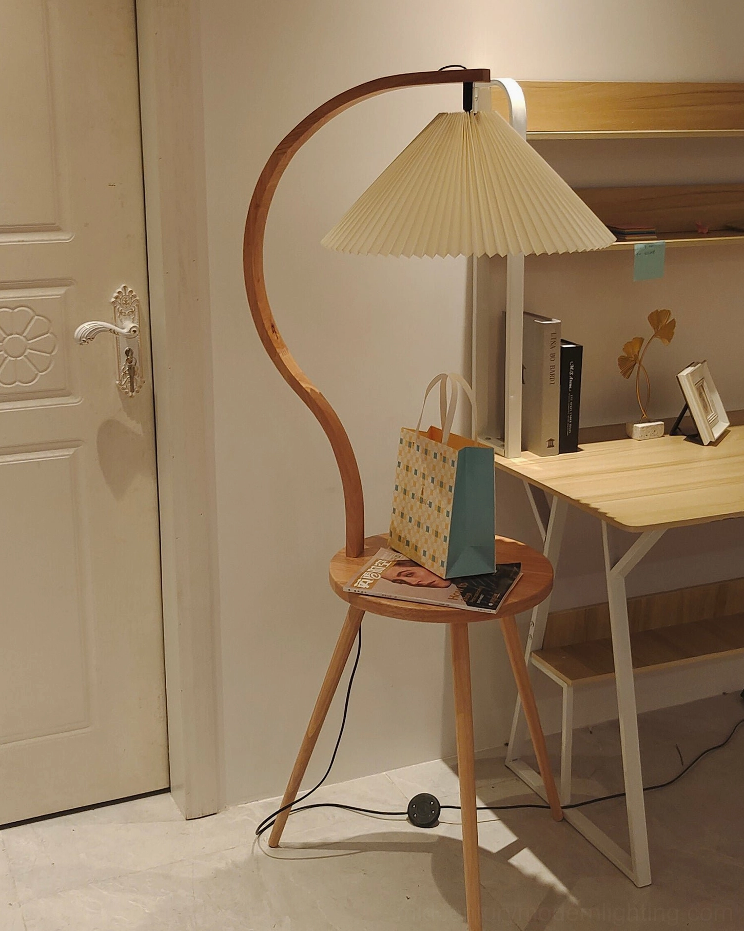 Caprani floor lamp illuminated in evening setting with warm ambient glow and side table styling