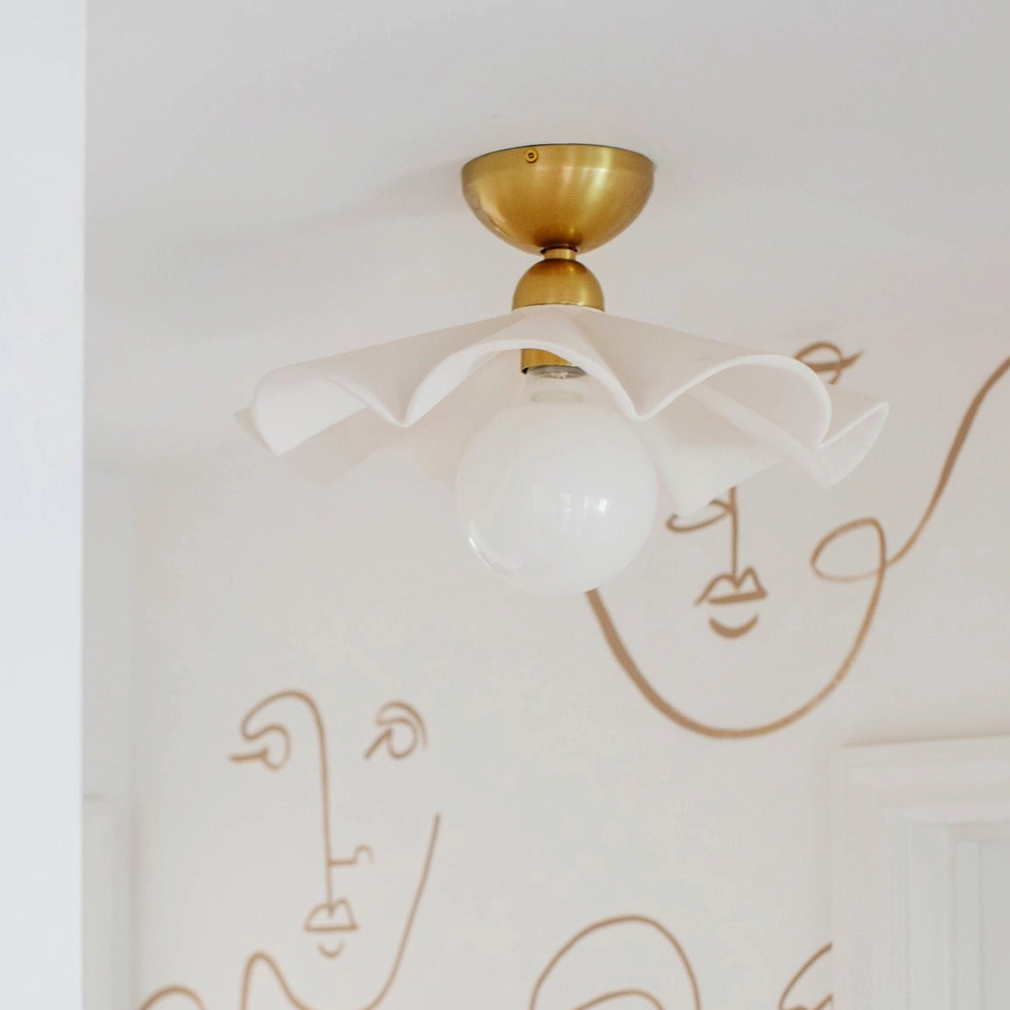 Capri flush mount ceiling lamp installed in modern bedroom with textured wallpaper and warm brass hardware accent wall