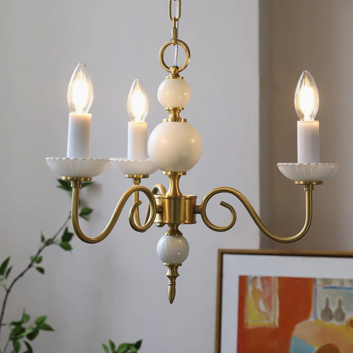 Carlita 4-light brass chandelier close-up with gold curved arms and white ceramic details illuminated
