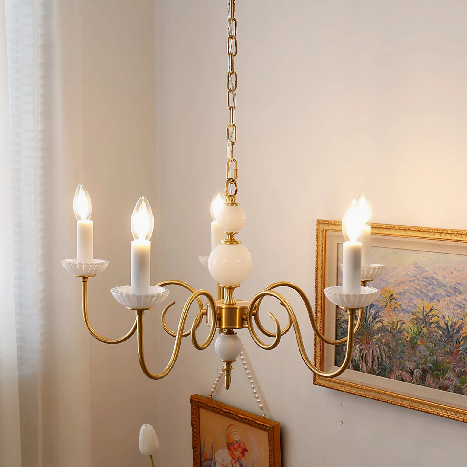 Carlita 5-light brass chandelier hanging in home space with landscape paintings and decorative flowers