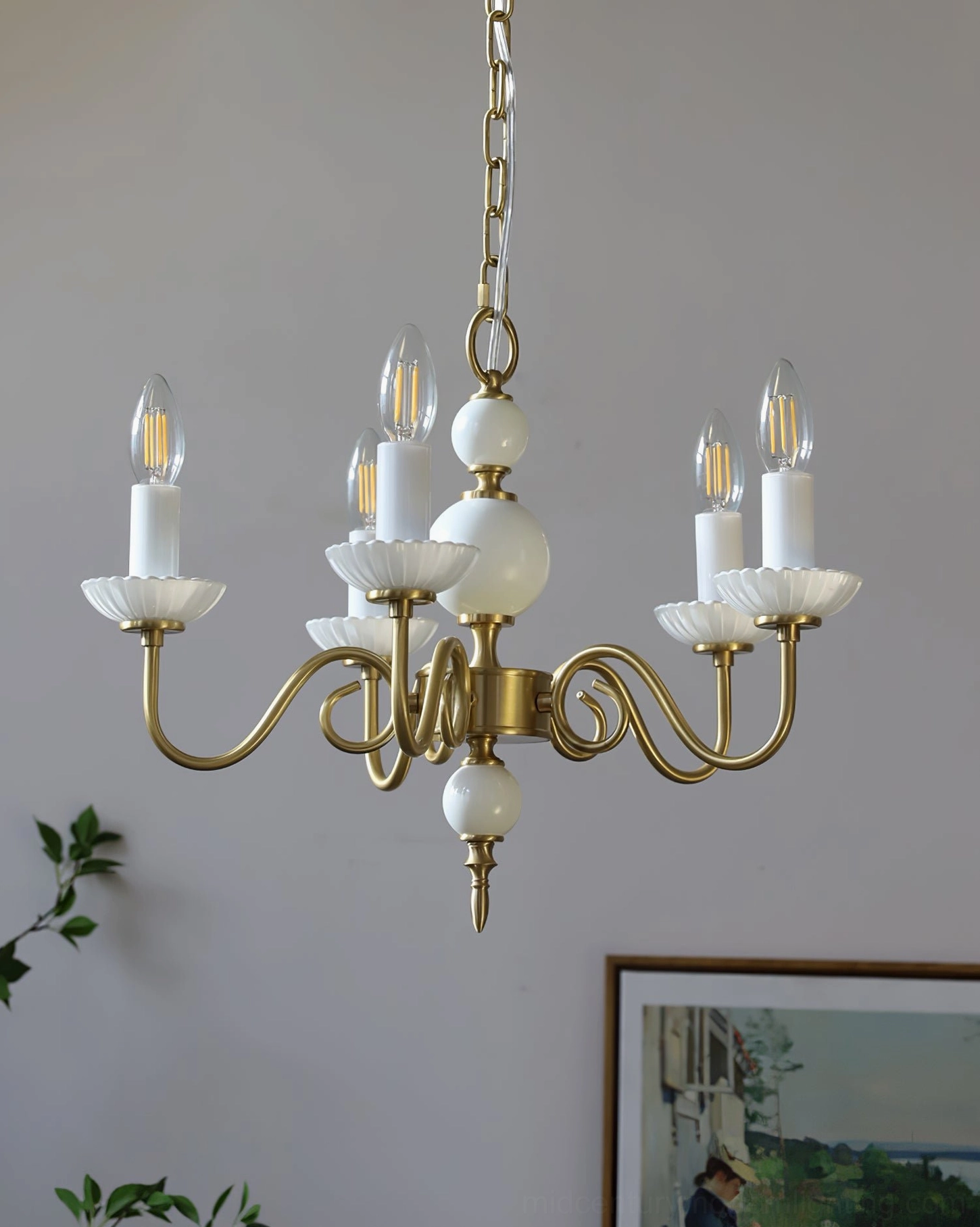 Carlita mid-century modern brass chandelier with white ceramic accents in neutral interior