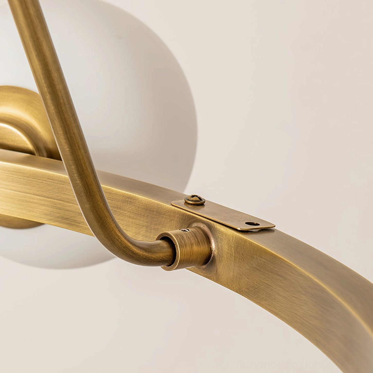 Close-up detail of Carolee chandelier brass metal joint and screw-fixed curved tubing, antique finish