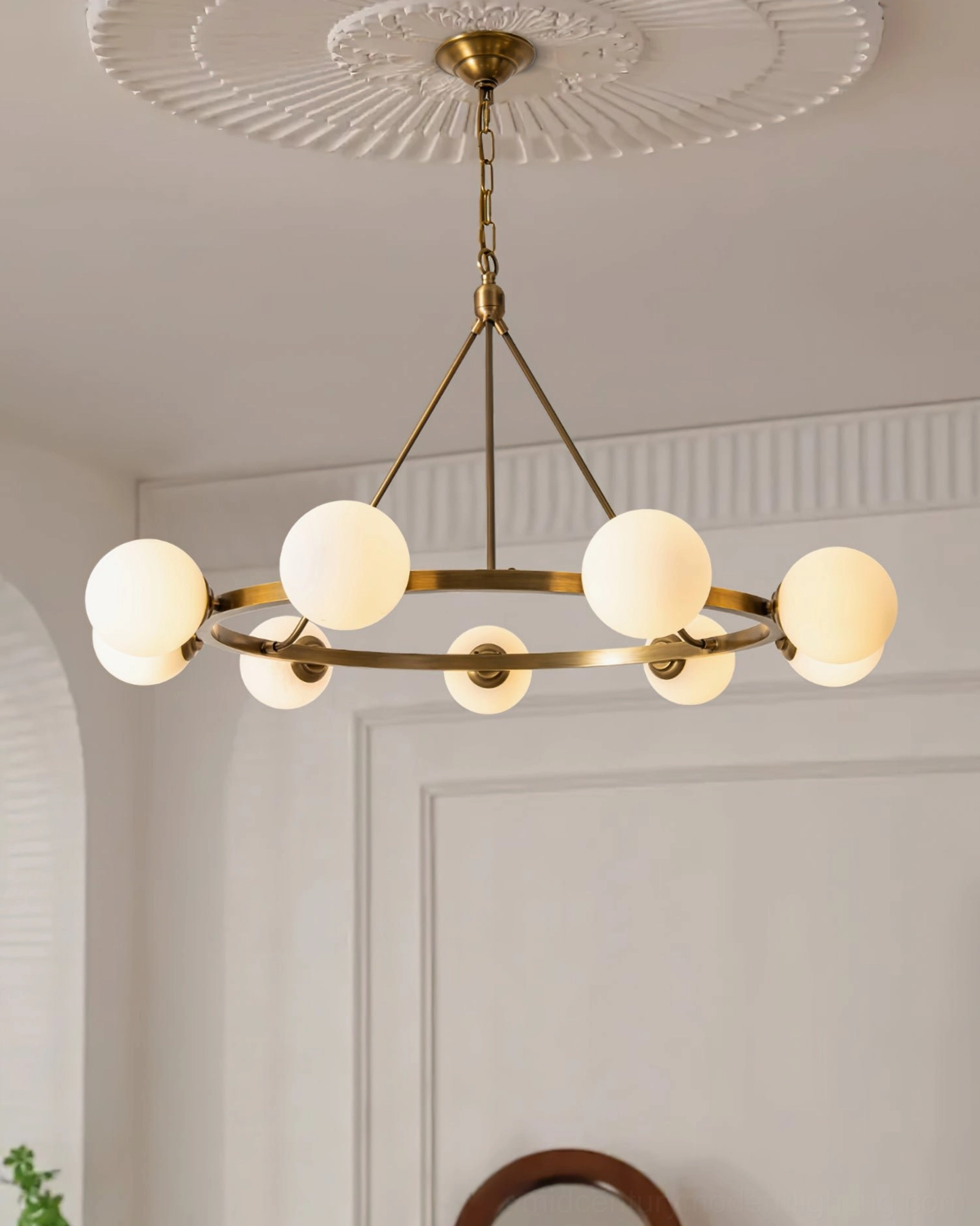 Lit Carolee brass pendant chandelier in elegant dining room with ceiling medallion, warm mid-century modern ambiance