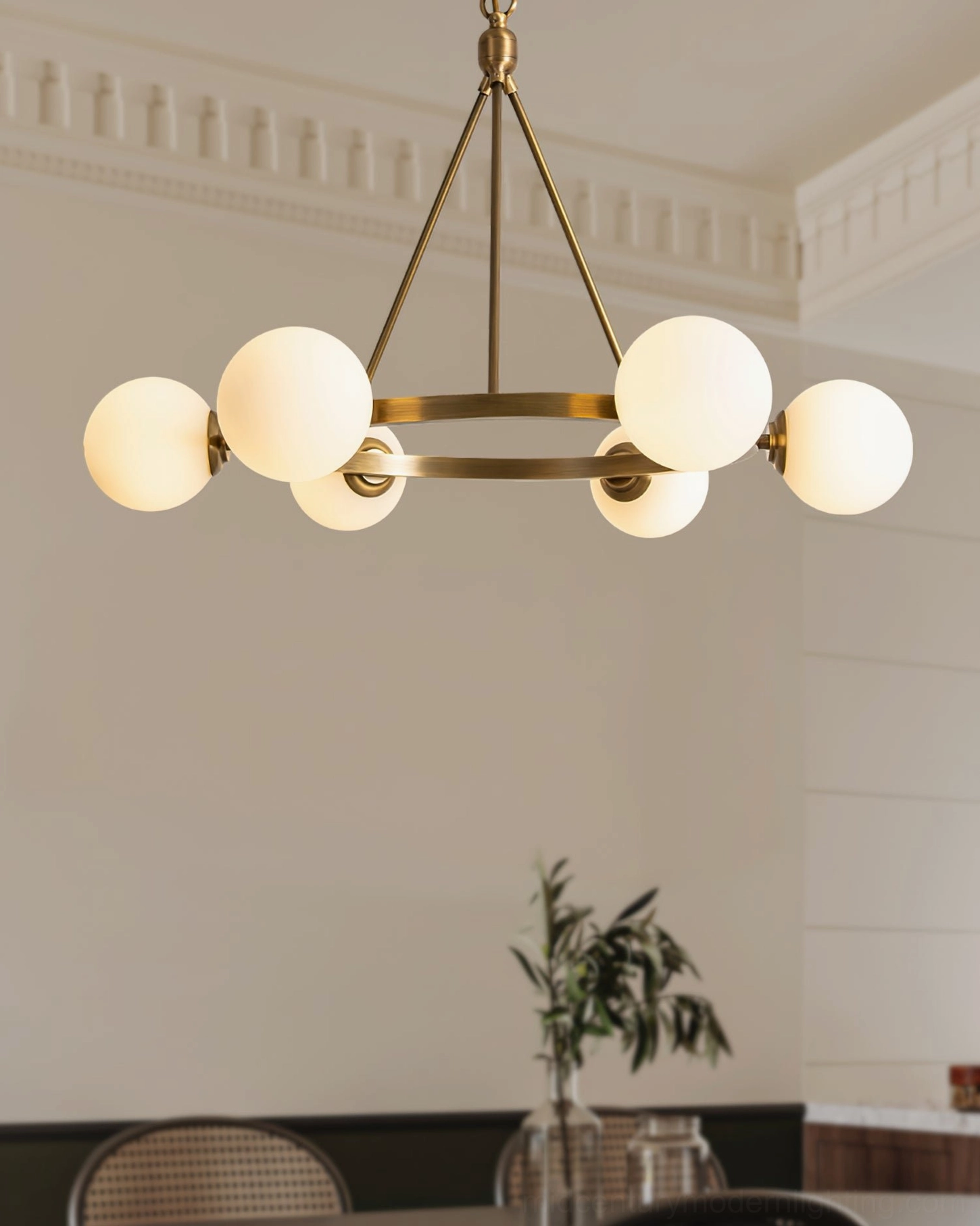 Lit Carolee brass ring chandelier in modern dining space with table and plant, cozy ambient home lighting