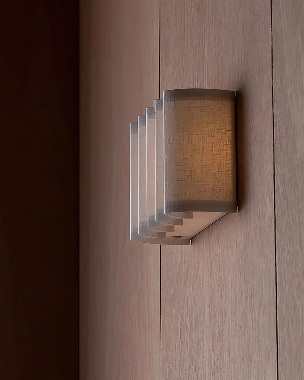 Cascade wall lamp side profile showing stepped ribbed half-cylindrical shape on light wood wall