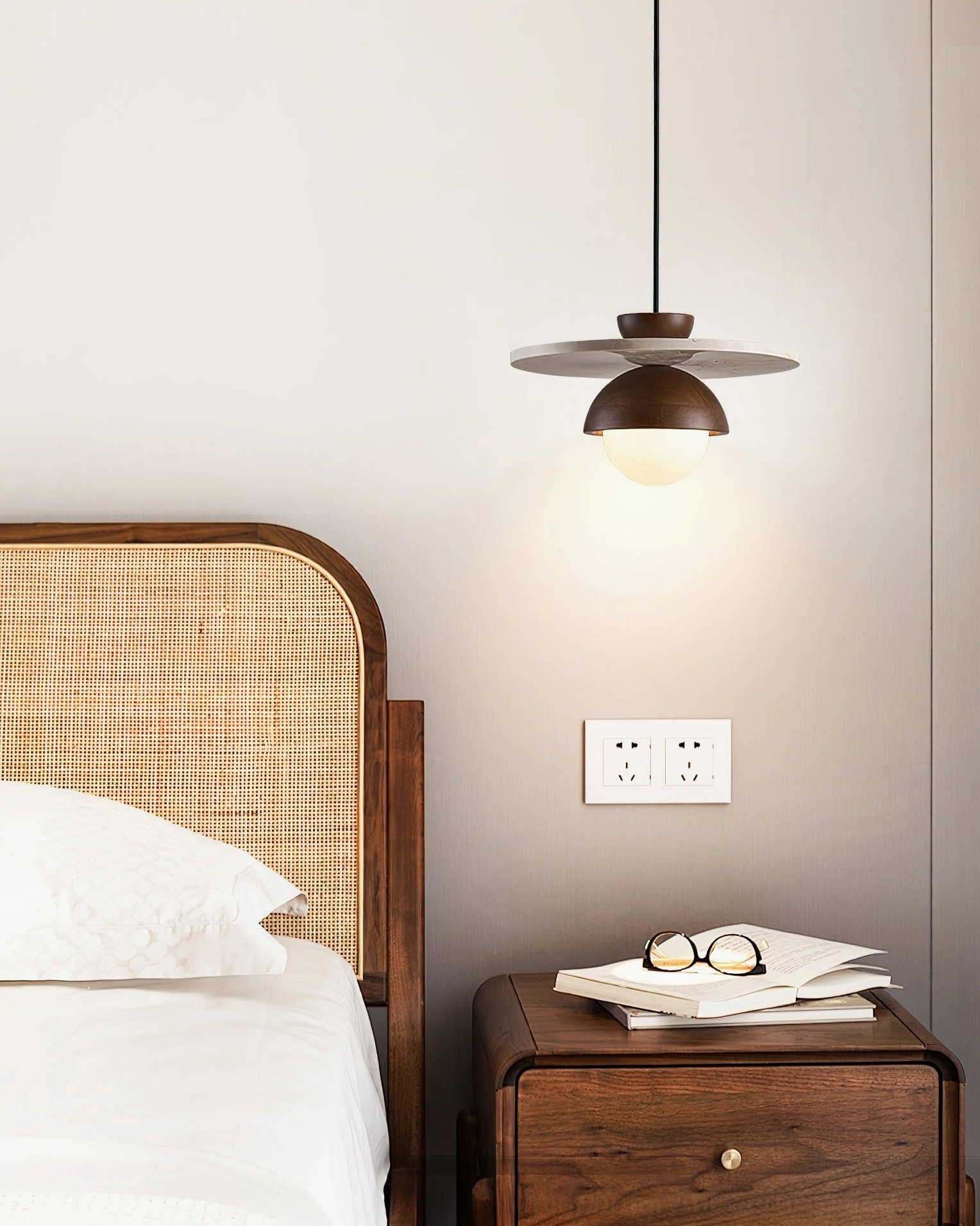 Cassini pendant light hanging above modern bedroom with rattan headboard and neutral tones
