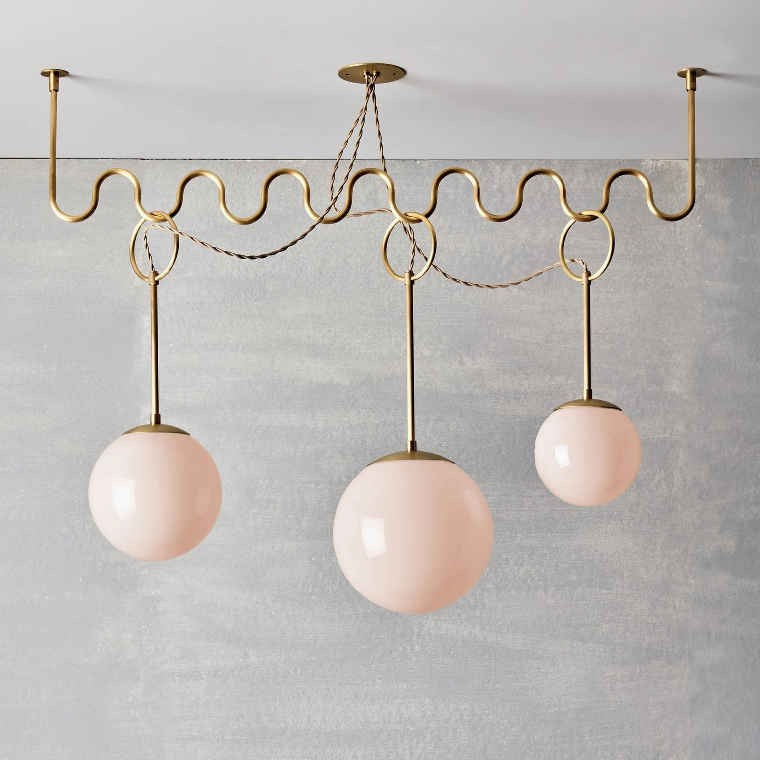 Three-head Cecil wavy chandelier with blush pink opal glass globes, sculptural brass frame design