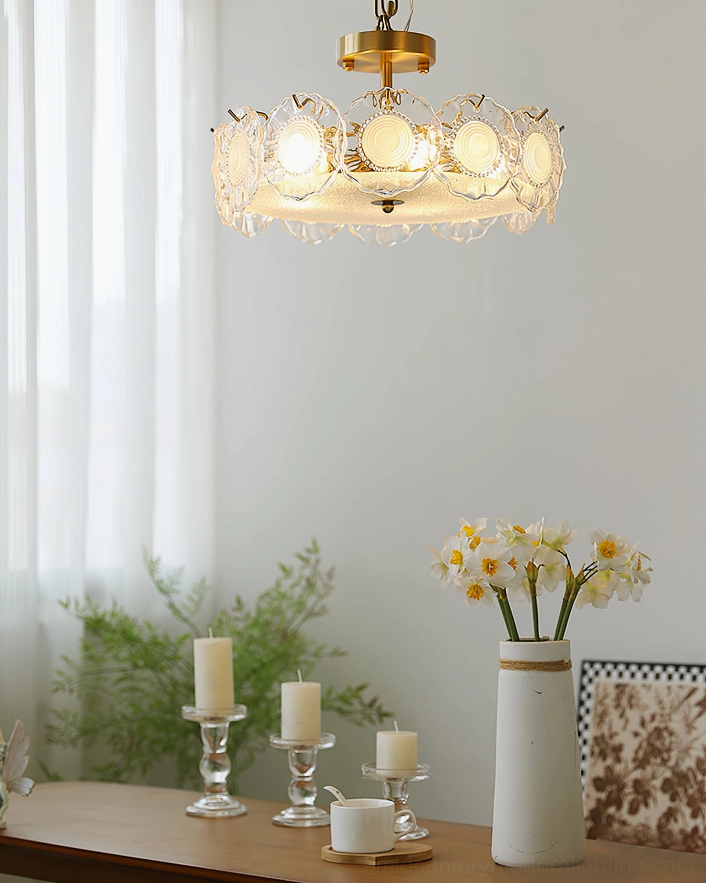 Glass ceiling lamp hanging above wooden dining table with flowers and candles in warm ambient setting