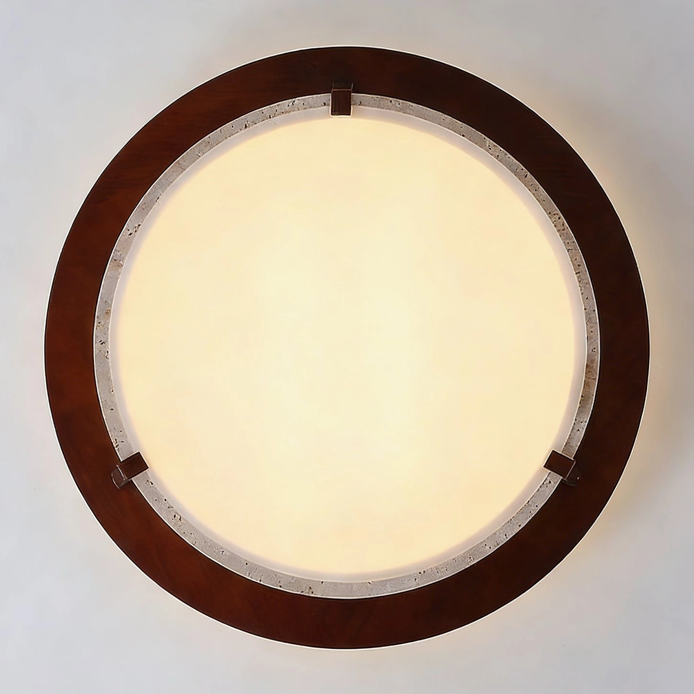 Illuminated frosted glass diffuser of travertine ceiling light, close-up of warm LED glow and finish