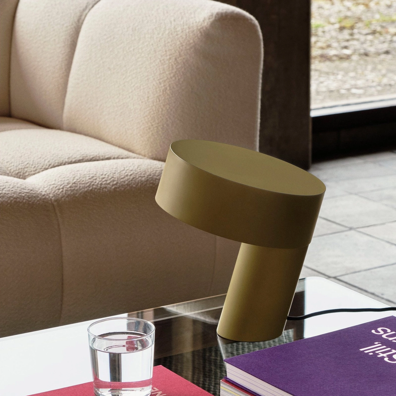 Celia khaki green table lamp on glass coffee table in modern living room with beige sofa, contemporary home décor