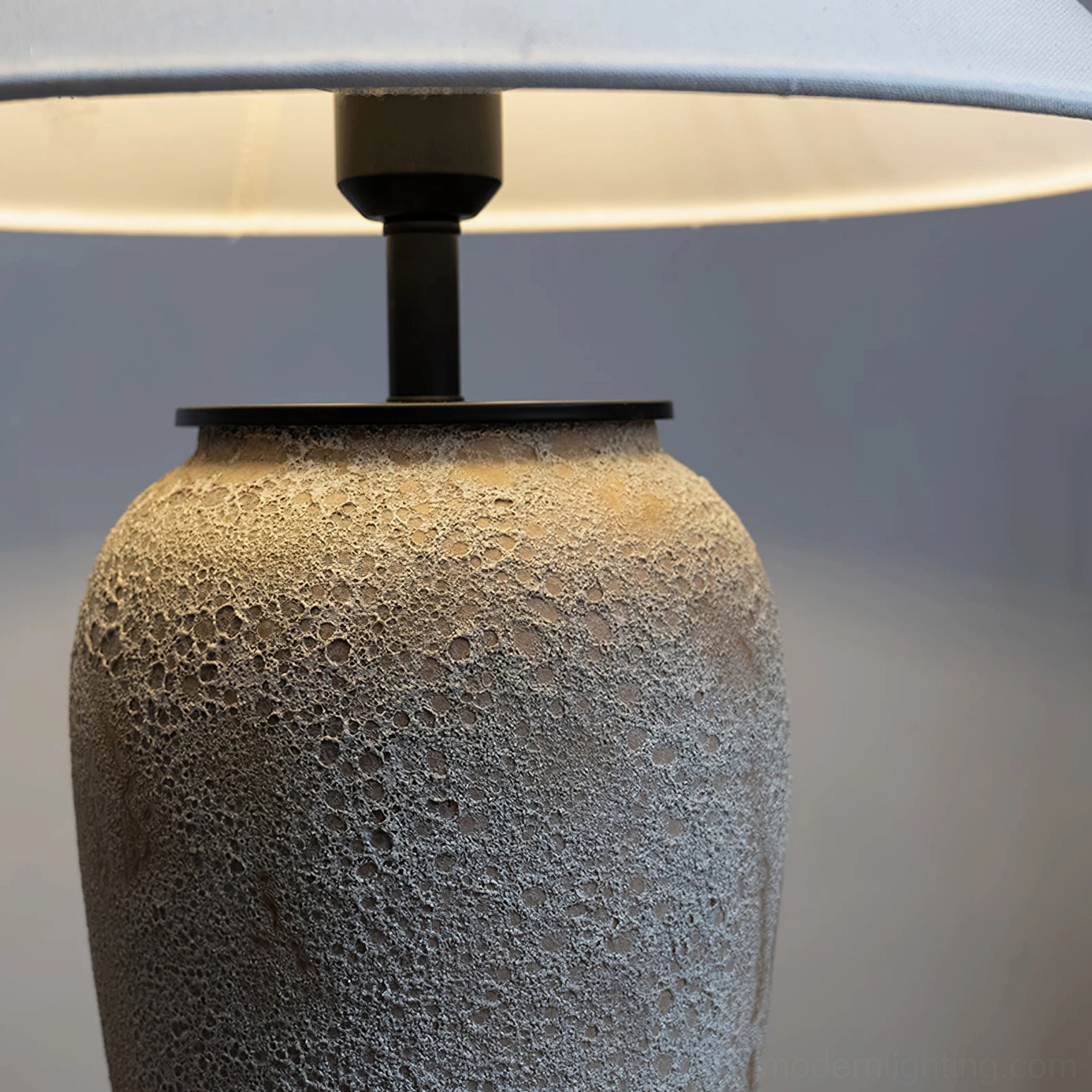 Close-up detail of porous textured ceramic lamp base showing artisanal finish and metal hardware