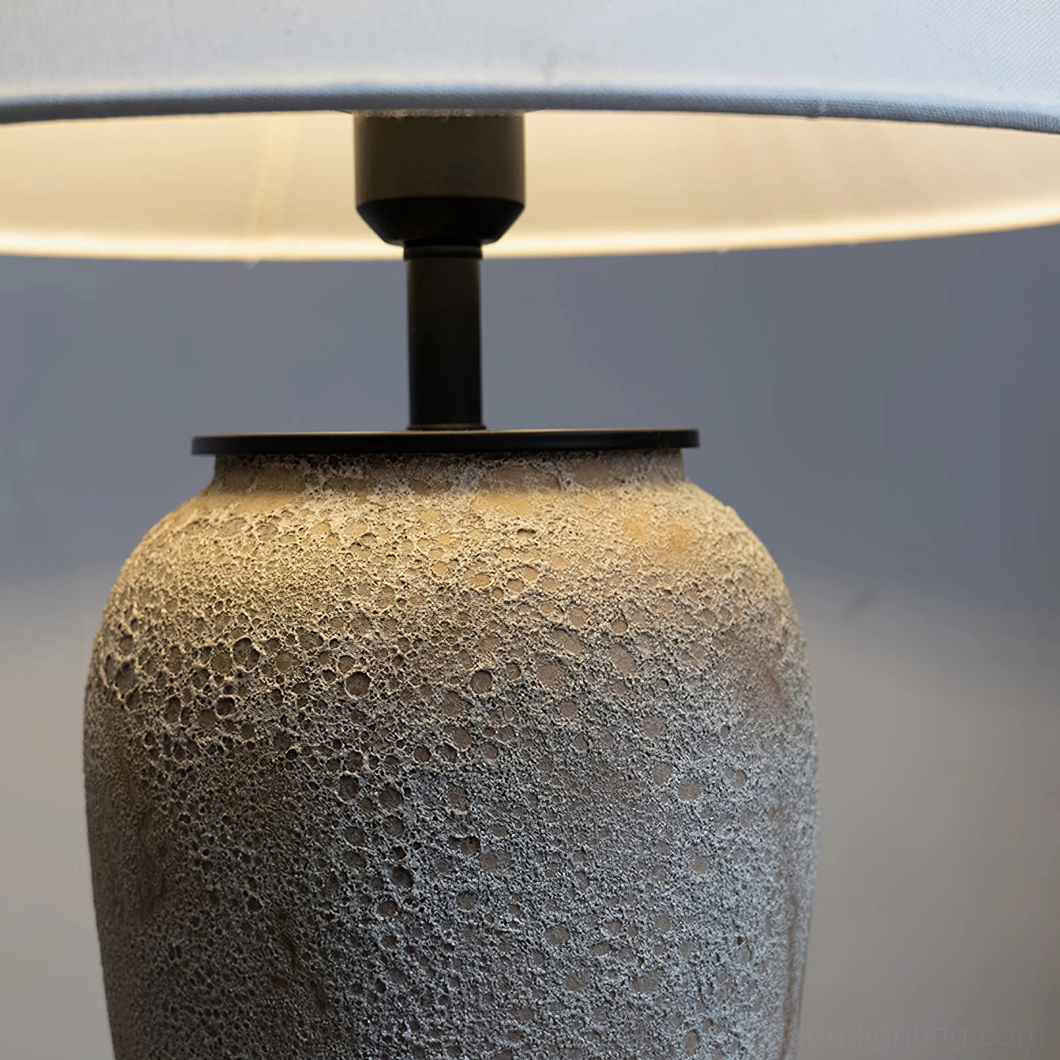 Top-down close-up view of ceramic lamp base showing porous rough surface texture and metal fixtures