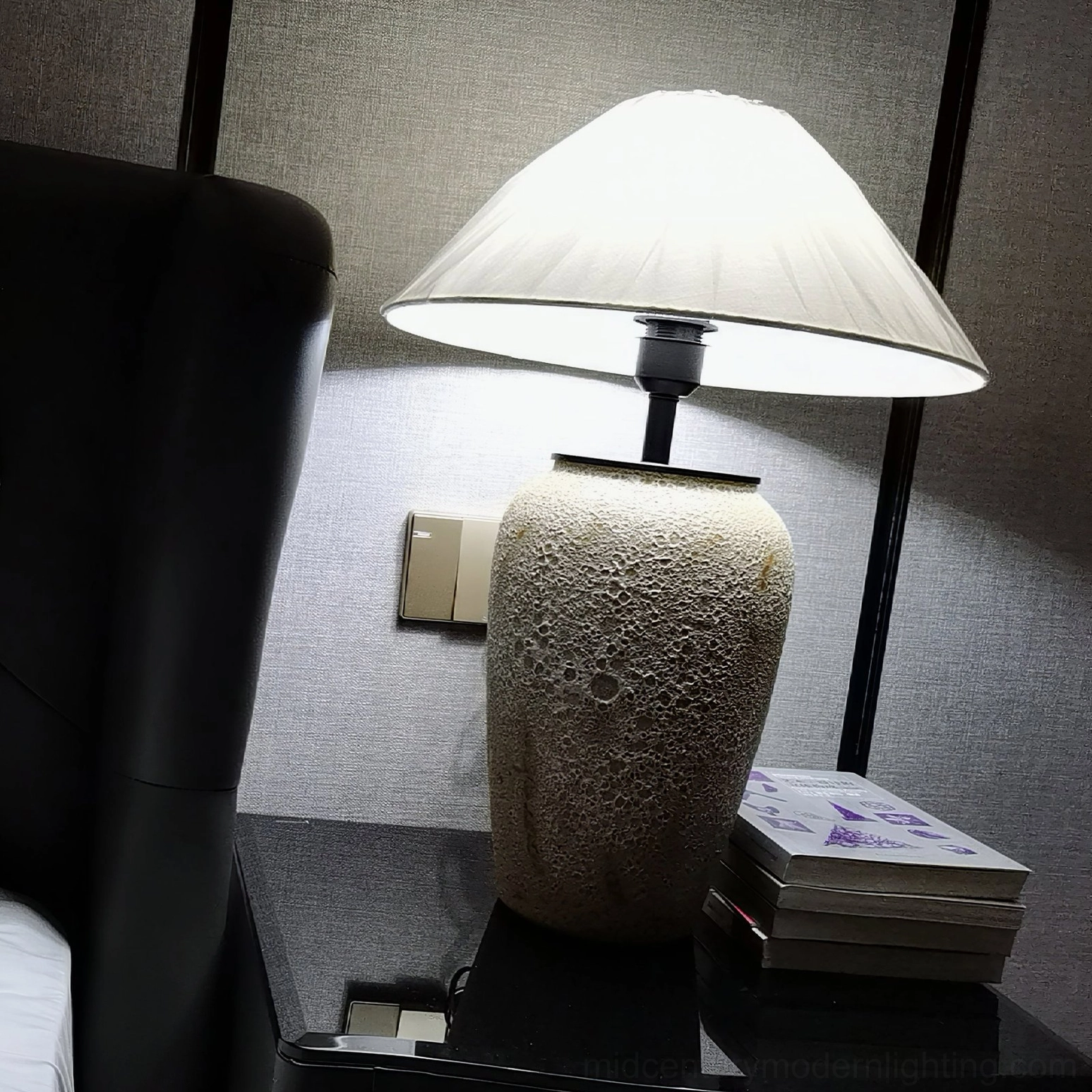 Modern ceramic table lamp on black glass side table next to leather sofa in contemporary living room