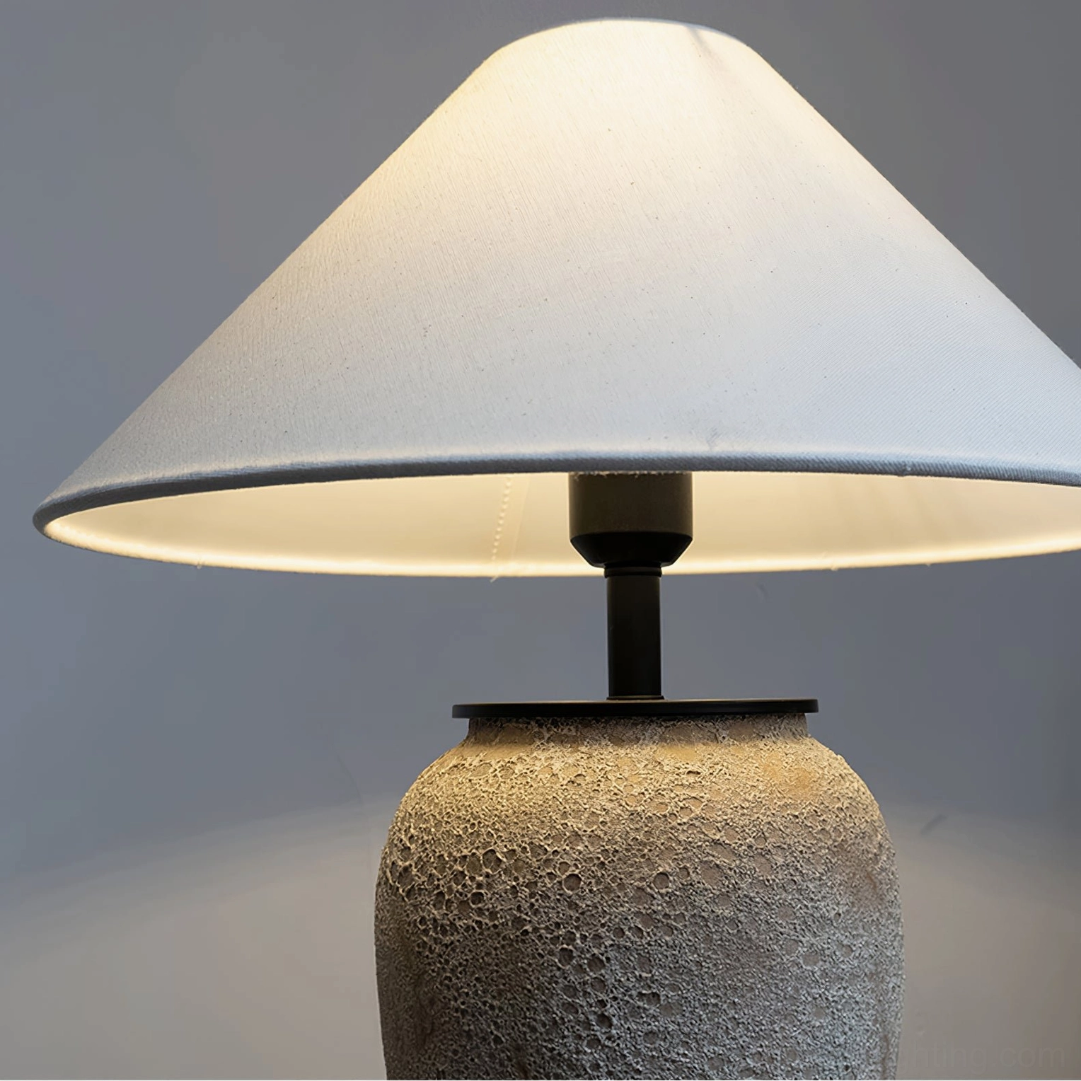 Low-angle front view of ceramic table lamp highlighting fabric shade edge and base construction