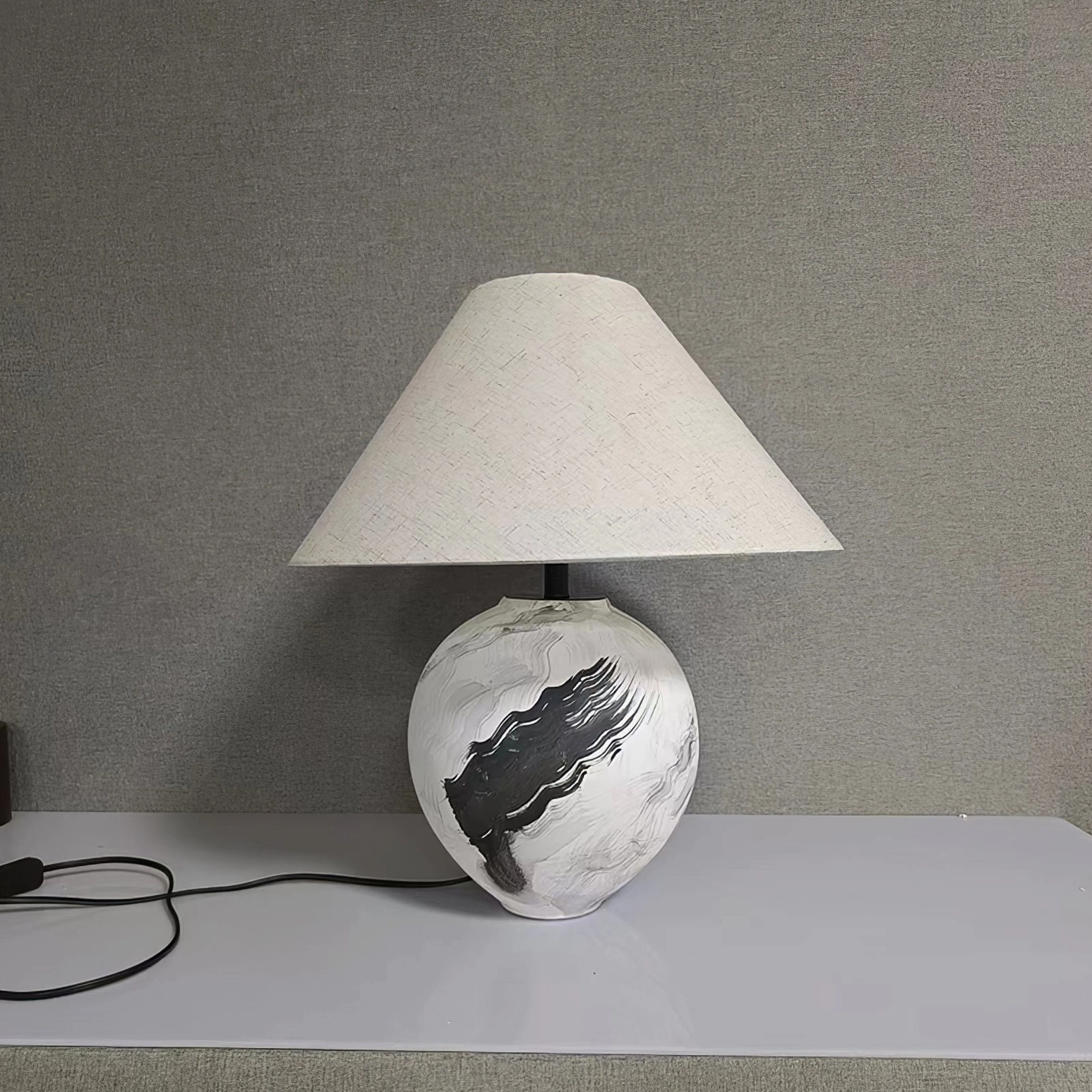 Ceramic table lamp with fabric shade positioned in contemporary interior design space