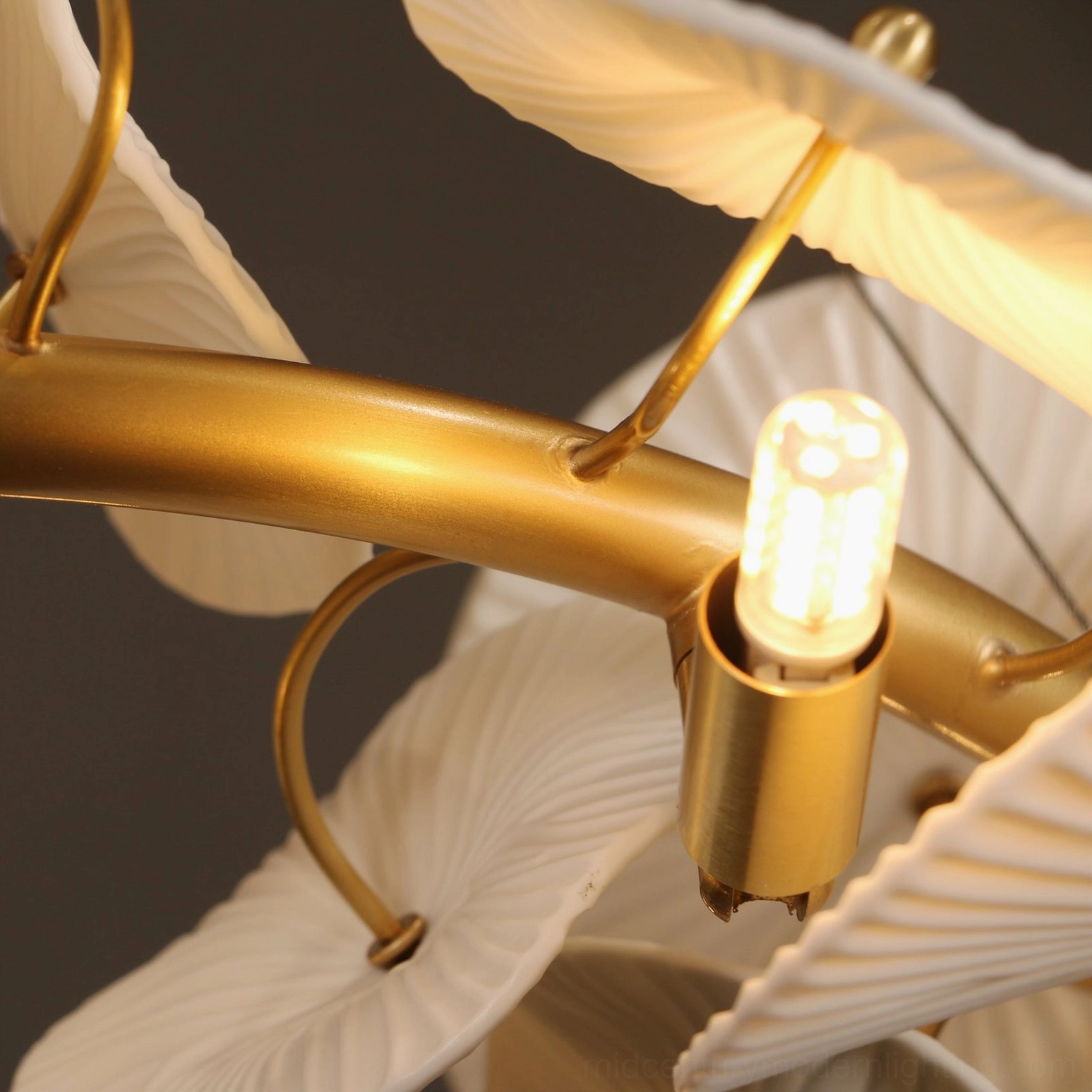 Low-angle close-up of ceramic wreath chandelier with Edison-style LED bulb and polished gold brass finish detail