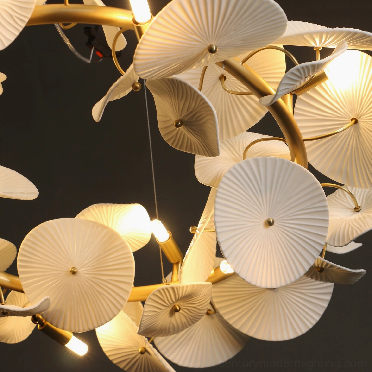 Overhead close-up of ceramic wreath chandelier structure with exposed G9 LED bulbs and curved brass frame construction