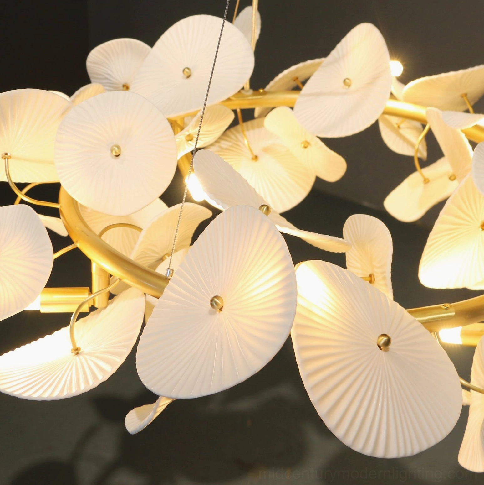 Illuminated ceramic wreath chandelier overhead view with warm yellow light glow highlighting clustered white petals