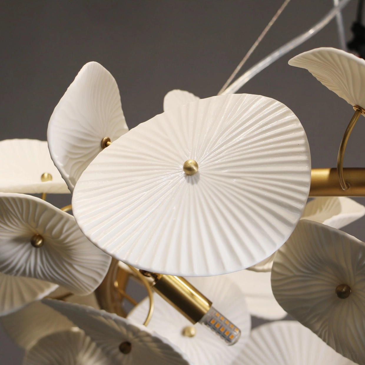 Side close-up detail of ceramic wreath chandelier petals with central gold stud and fine pleated texture refinement