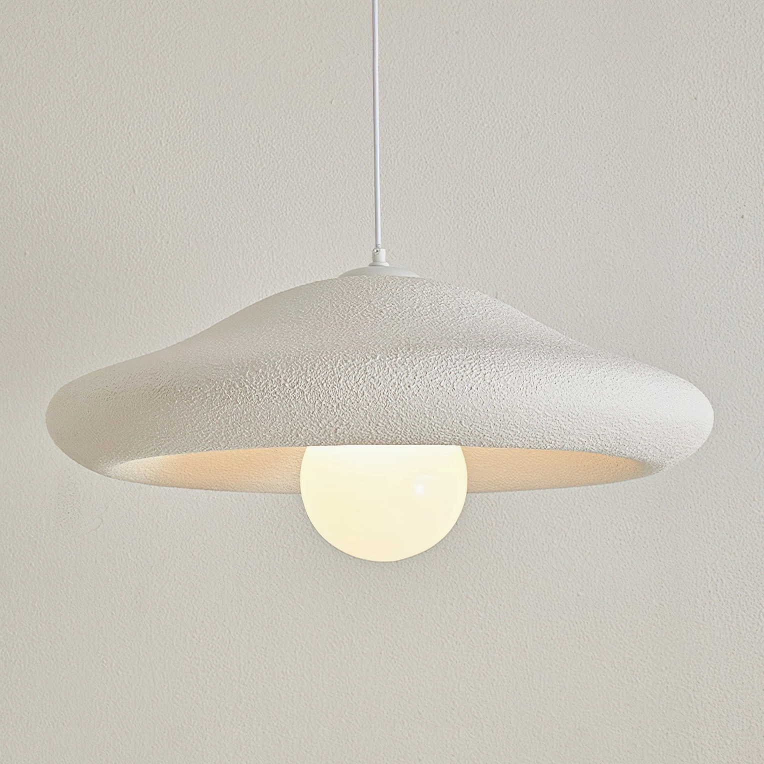 Chalk pendant light with warm glowing bulb exposed in minimalist clean design aesthetic