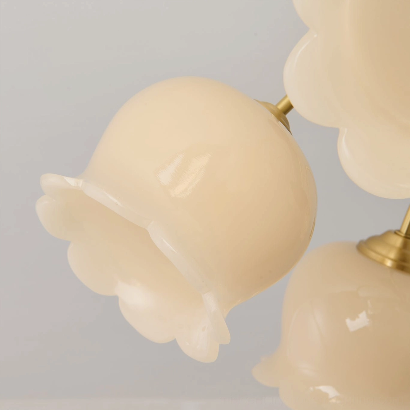 Macro close-up of ruffled bell-shaped glass flower shade with brass mounting hardware, textured cream glass detail