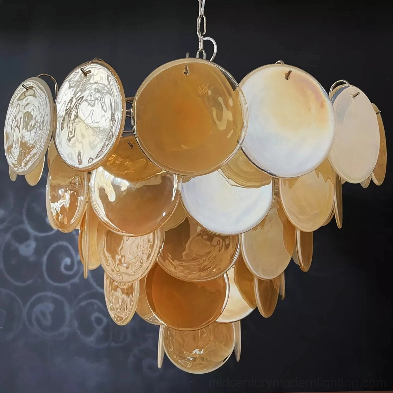 Low angle close-up revealing layered tiered structure of mixed clear and amber Murano glass discs