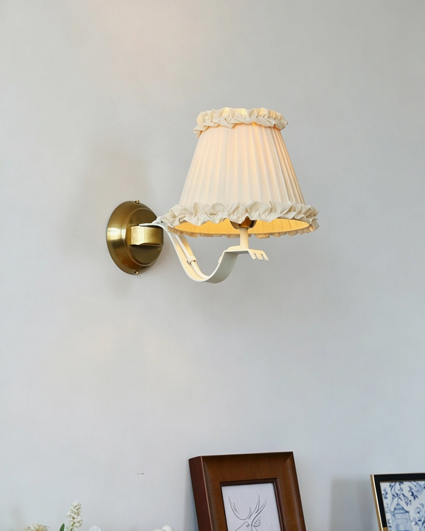 Chantal sconce front view showing delicate ruffled shade edge with framed art below on light wall