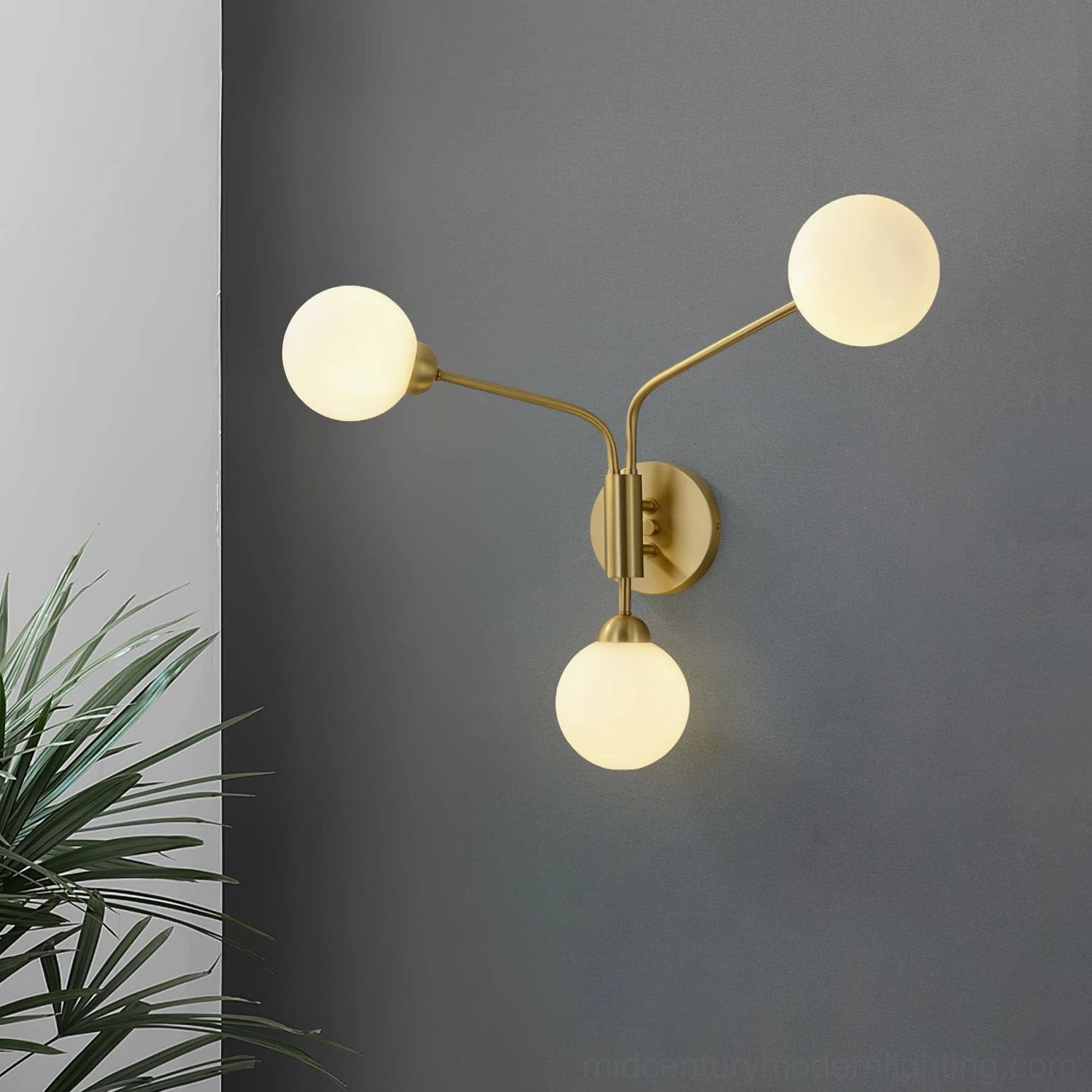 Chelso asymmetrical wall lamp with brass metal and frosted glass green plant backdrop