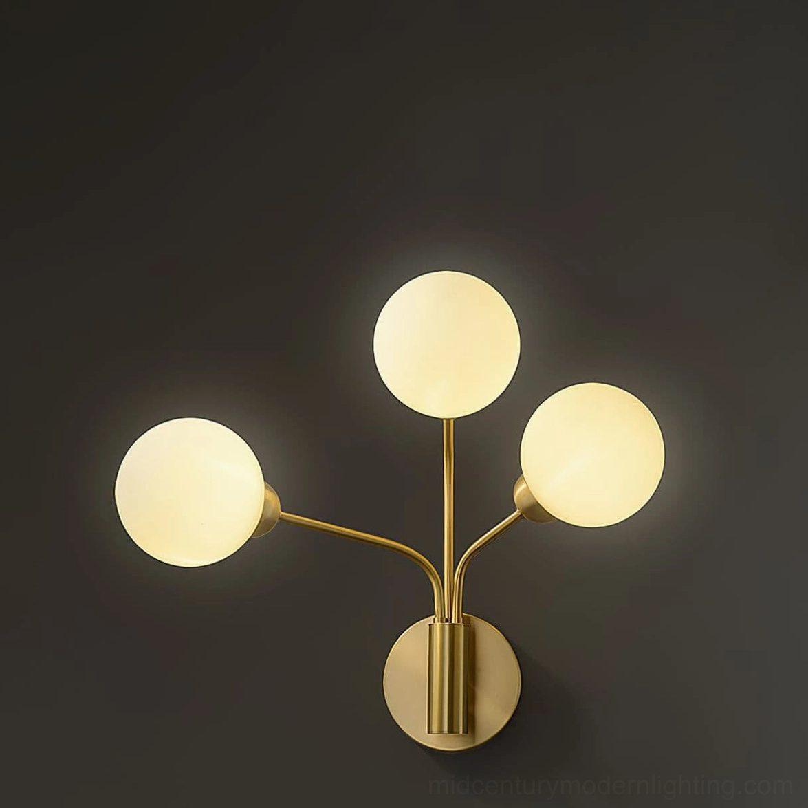 Chelso wall sconce illuminated showing brass metal and lit frosted glass modern luxury