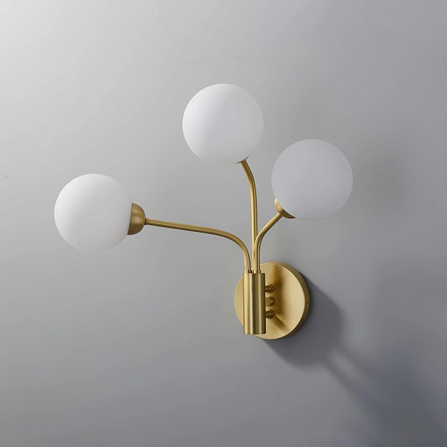 Chelso three-light globe wall sconce brushed brass white frosted shades gray wall