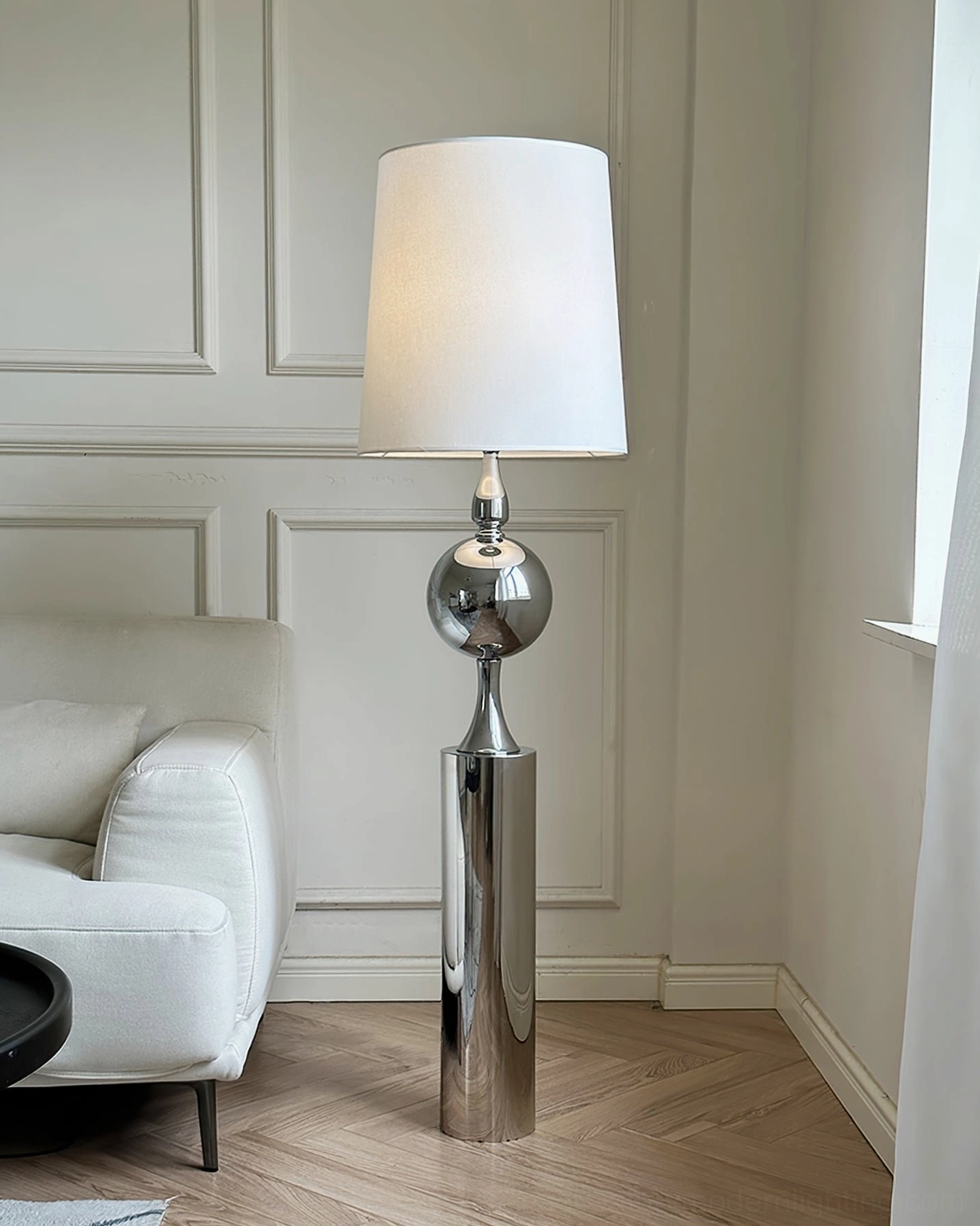 Silver chrome floor lamp with fabric shade positioned in minimalist living room beside white sofa - contemporary interior design