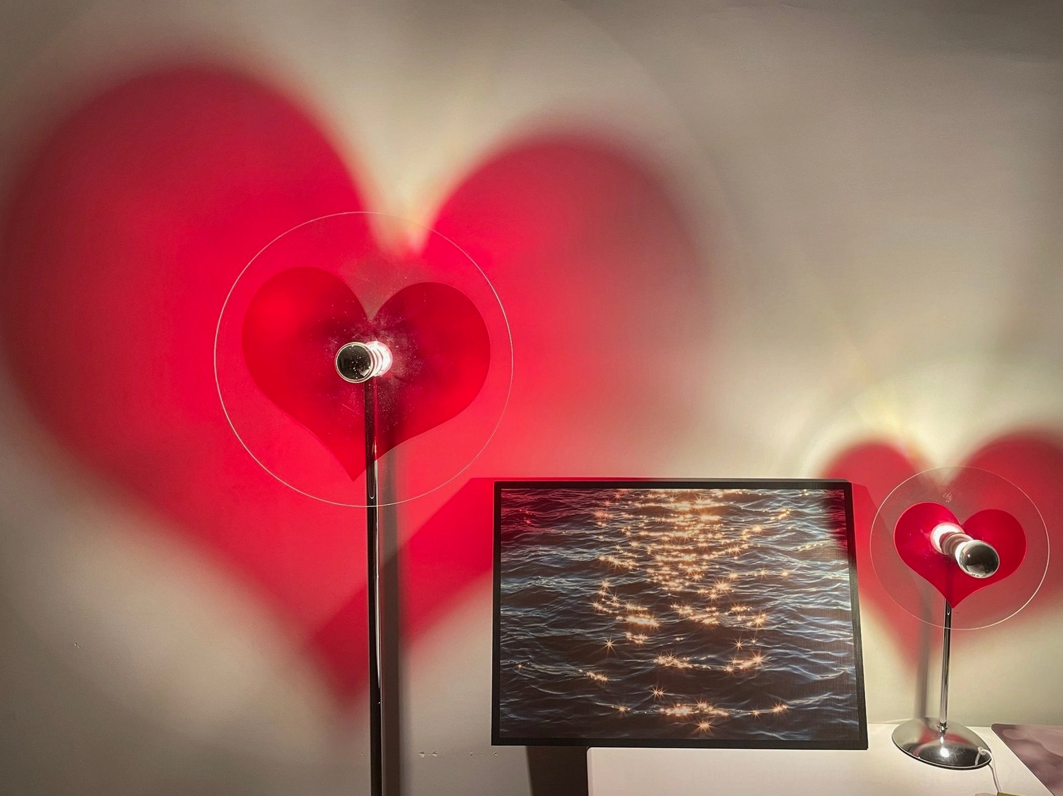 Chrome heart projection floor lamp creating decorative shadow in modern home space