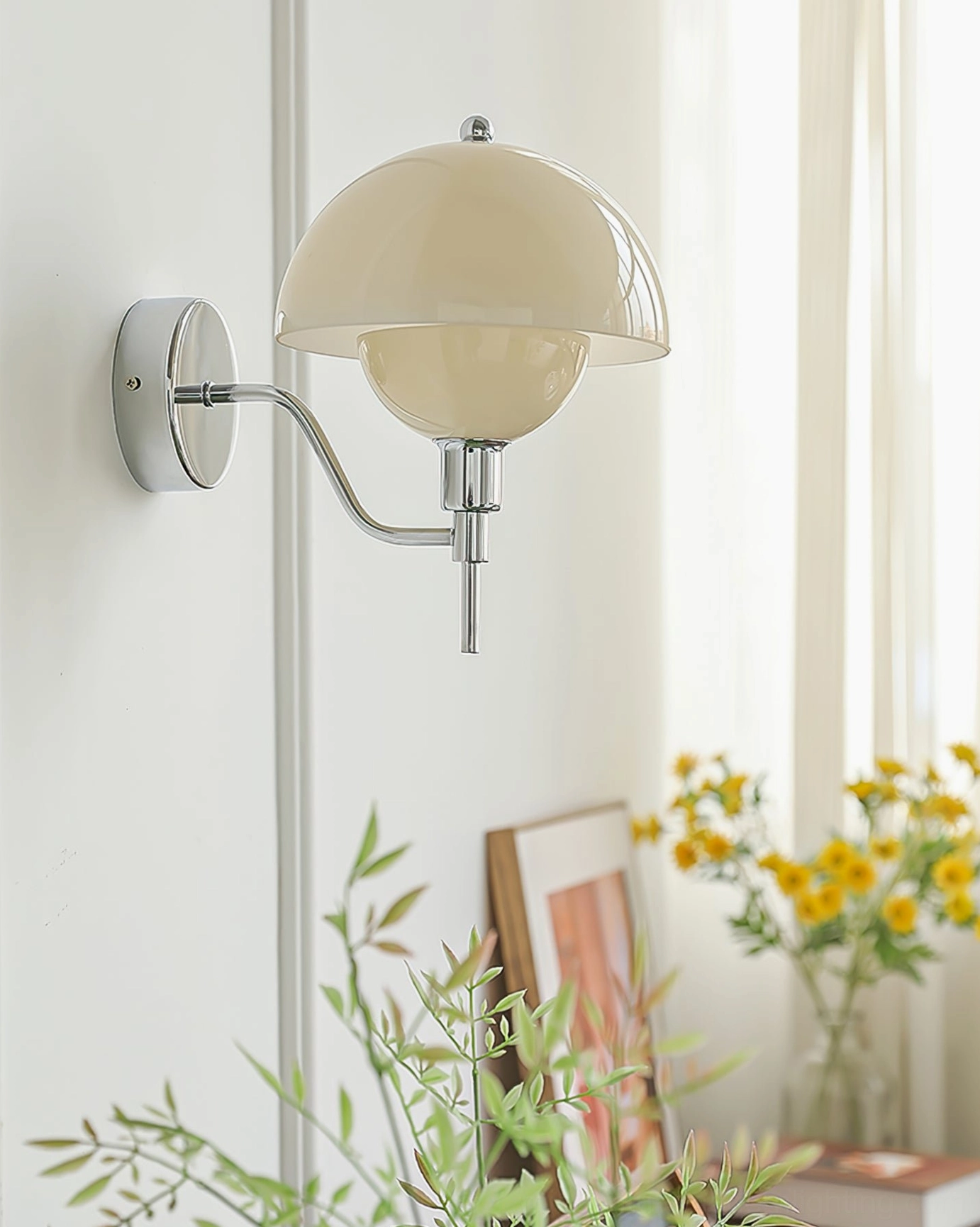 Chrome anchored orb wall lamp mounted on wall in minimalist home interior with plants and floral decor