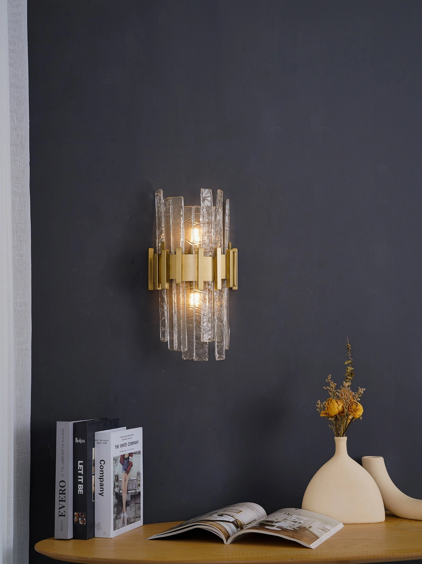 Brushed gold dual-light wall sconce with textured glass on solid blue wall background