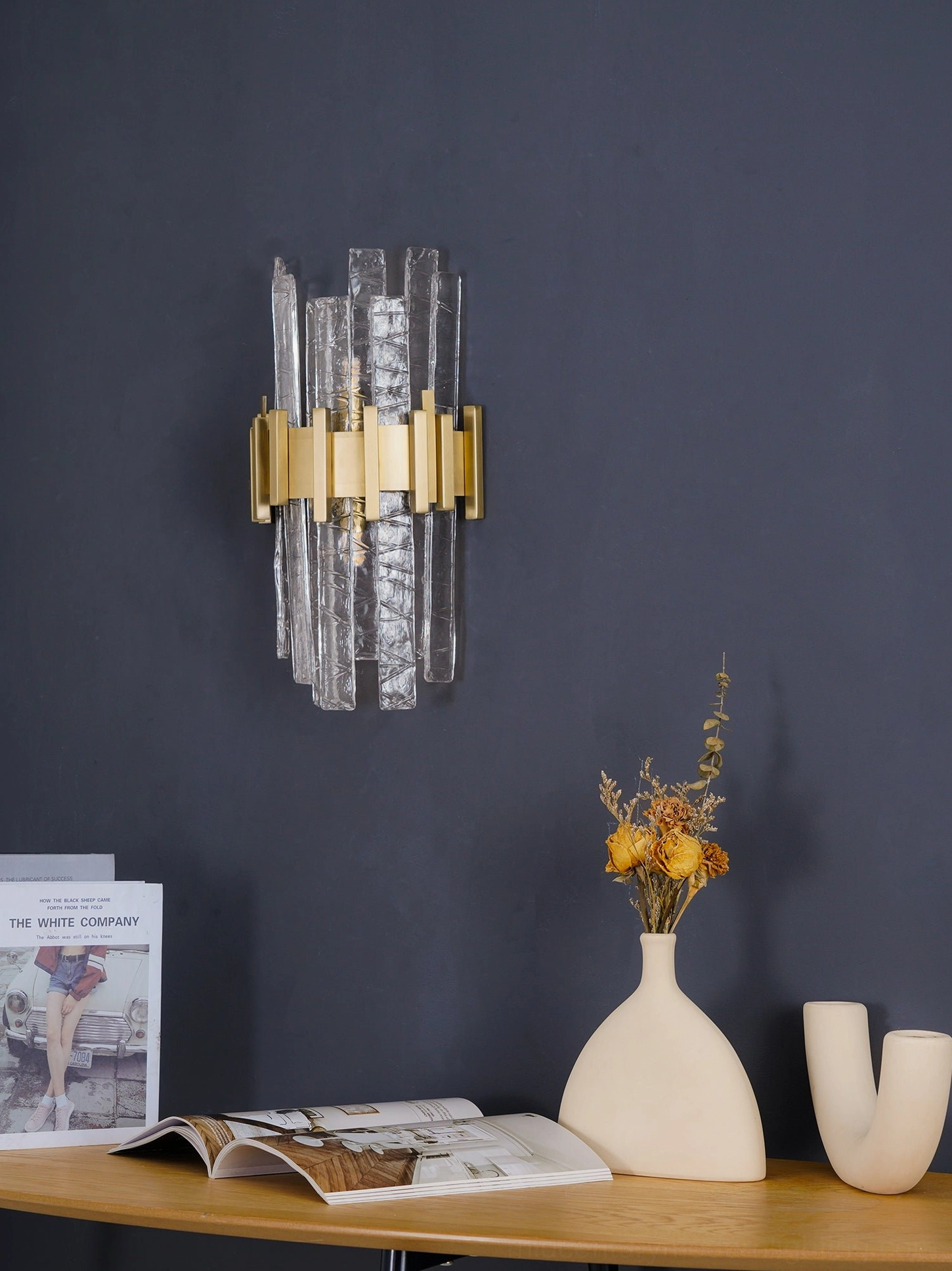 Modern luxury textured clear glass wall sconce with gold metal base and ambient lighting