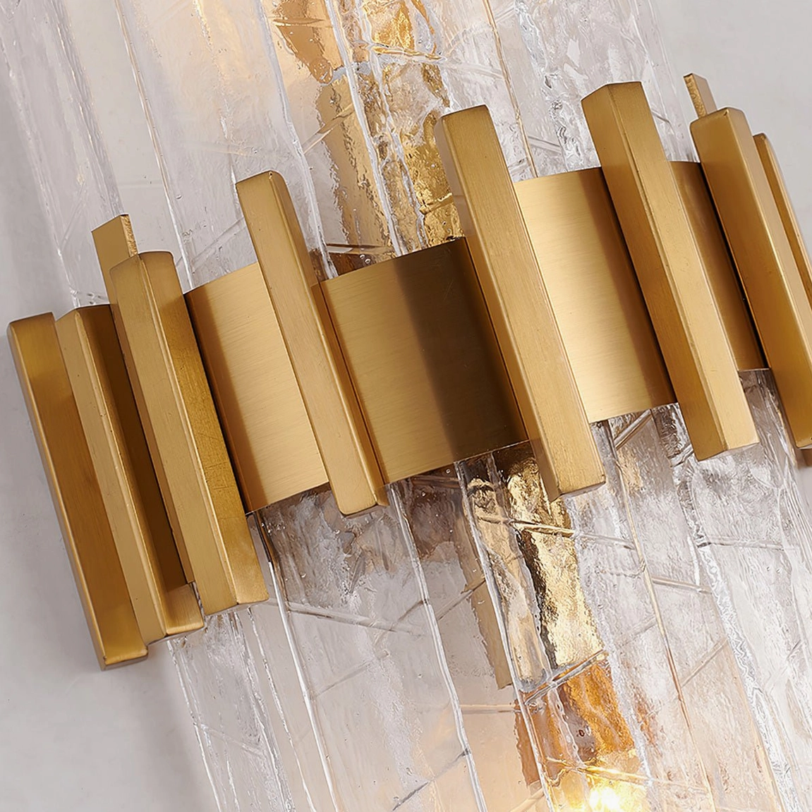 Close-up detail of Ciro wall lamp showing layered textured glass and linear brushed gold metal frame