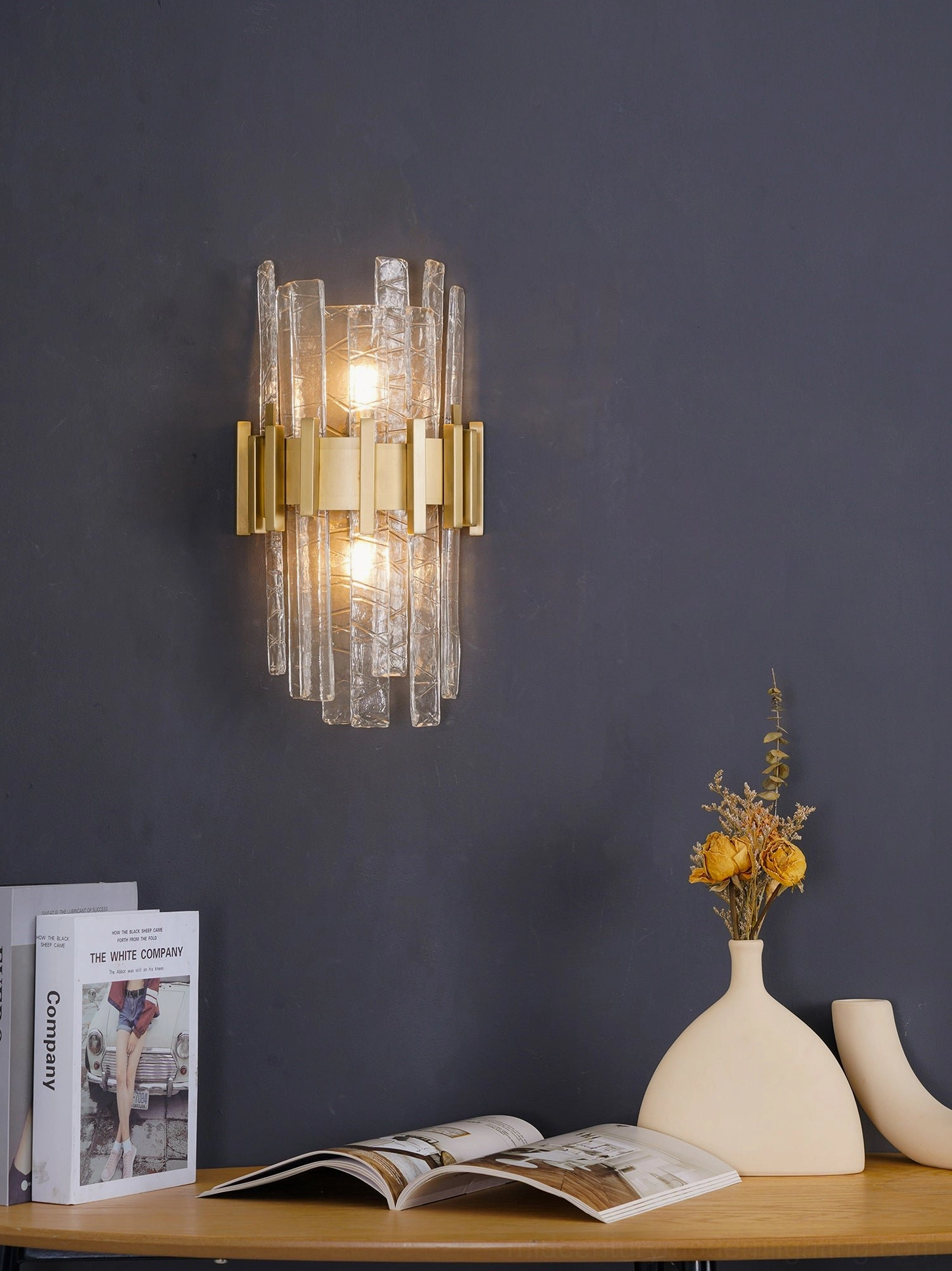Luxury wall sconce with warm glowing bulbs on dark blue accent wall, atmospheric lighting