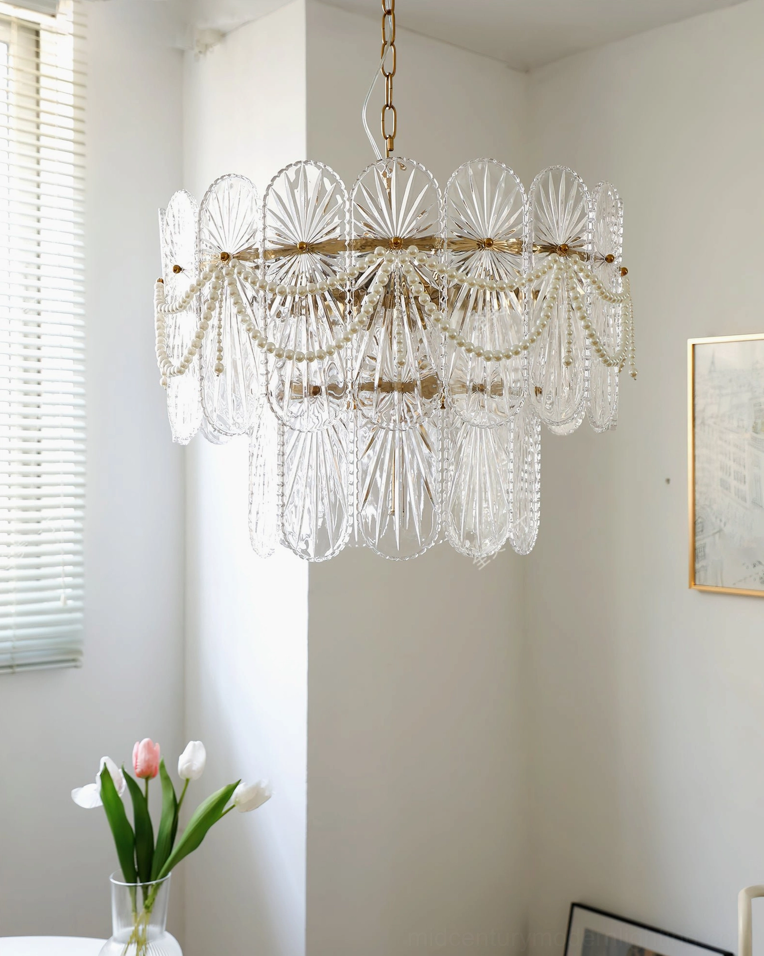 Clear ribbed glass chandelier with silver-toned metal frame hanging in bright apartment interior