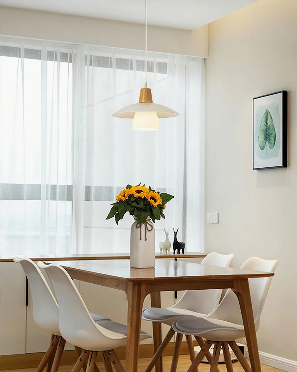 Close-up of minimalist pendant light fixture showing rubber wood cap detail and glass shade connection