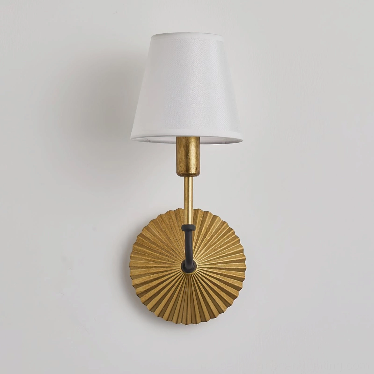 Clove brass wall lamp unlit displaying white fabric shade and sculptural fan-like metal base, front side view on white wall, vintage design